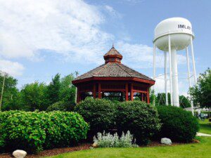 Horizontal shot of city water tower behind garden featuring a red gazebo