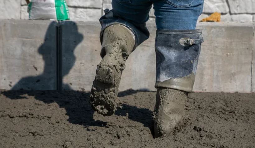 A worker's feet submerged in concrete