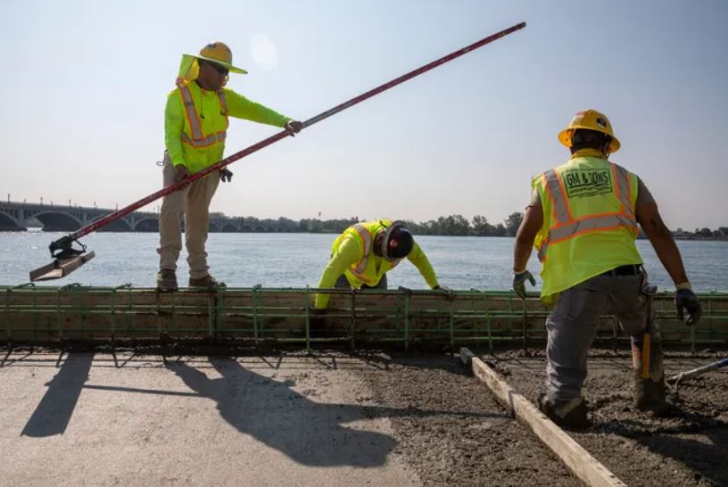 Construction workers smooth out the poured concrete